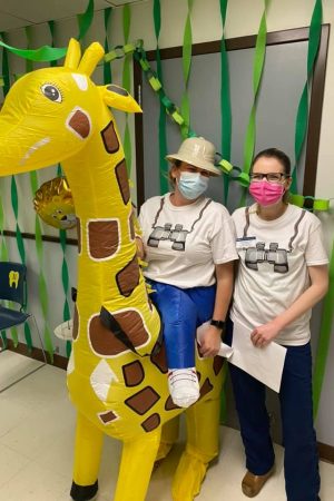 Two masked people, and one of them with a giraffe costume.