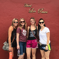 Four women standing in front of a red wall.