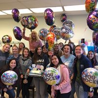 People with a cake and ballons.