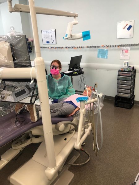 A dental hygienist cleaning a kids teeth.