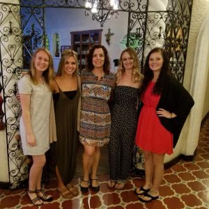 Five women smiling and posing for a photo.