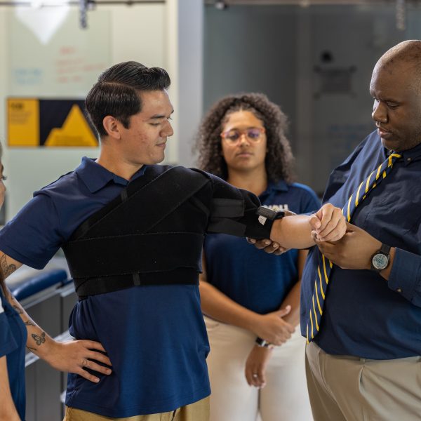 Select this image to be directed to more information on additional program fees. Faculty member examines a patients arm. 