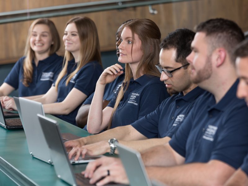 Students wearing matching blue polos sit in a lecture.