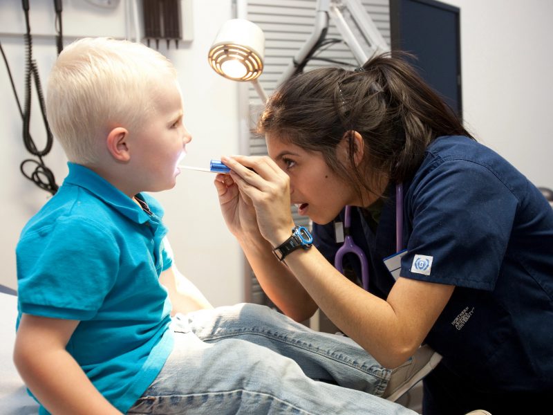 Nurse examining a pediatric patient's mouth.