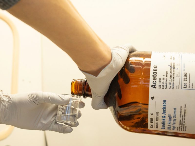 Student is pouring acetone into a small beaker.