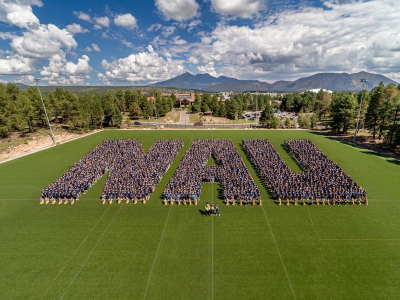 Hundreds of people forming the letters N A U.