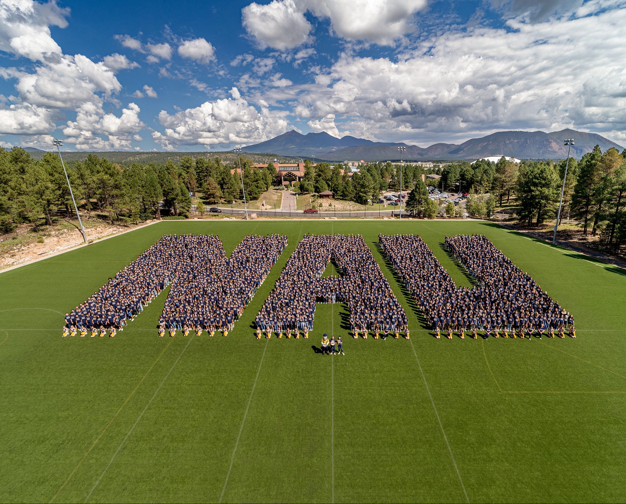 Hundreds of people forming the letters N A U.