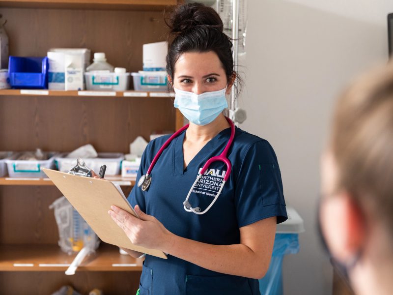 Nursing student talking to a patient and making notes.