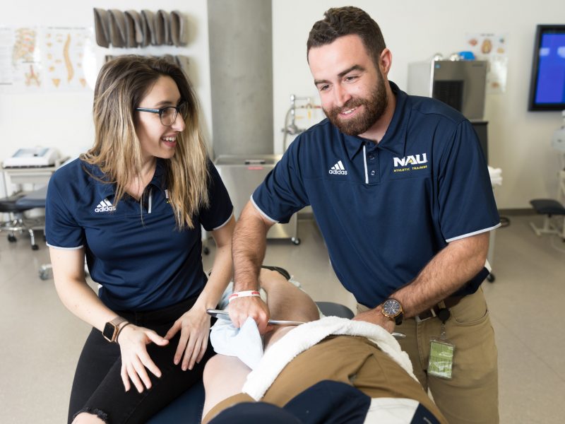 Two Athletic Training students practicing on another student.