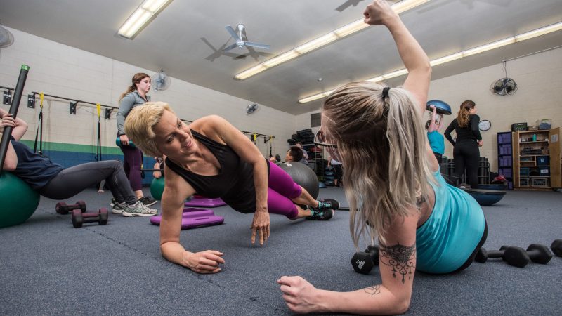 Physical Education student exercising with teacher in a gym setting.
