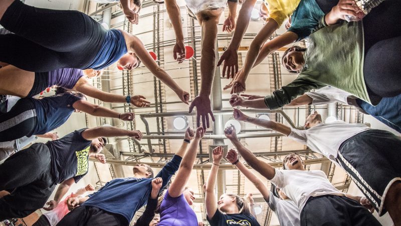 Students in a circle and lifting up their hands.