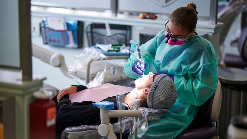 A dental hygienist cleaning a students teeth.