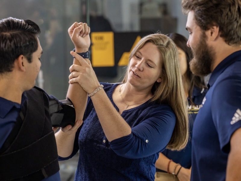 A person showing a student how to wrap an arm.