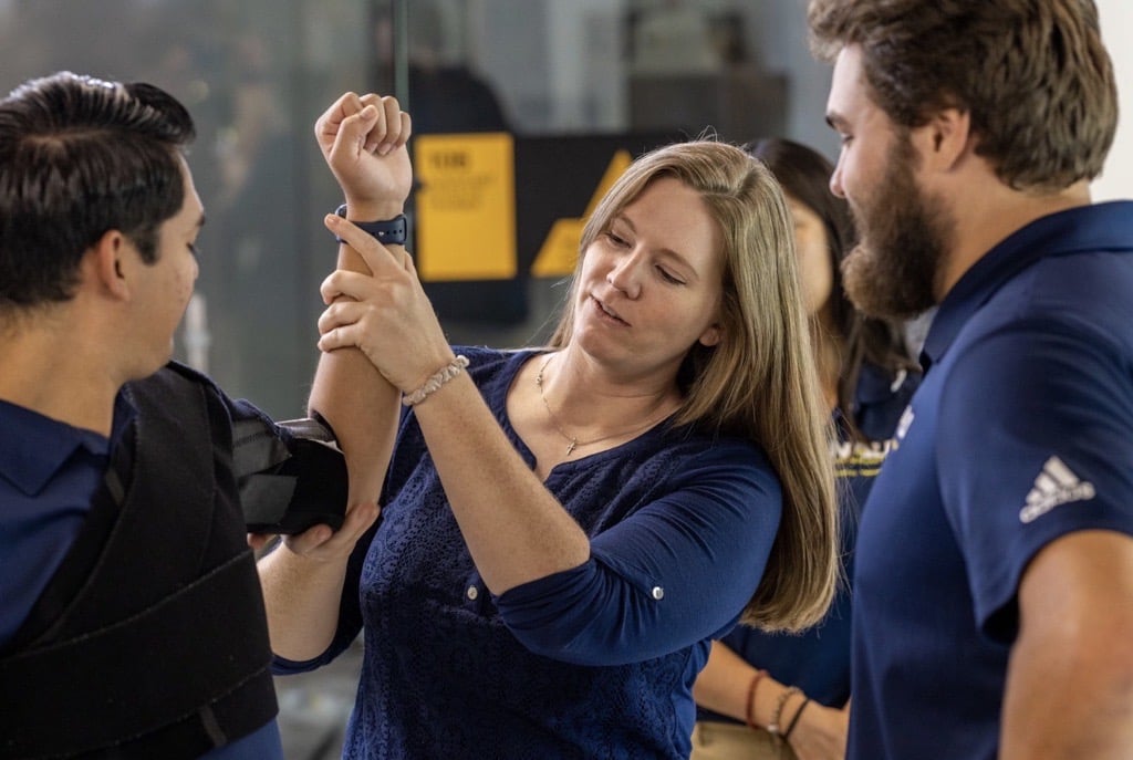 A person showing a student how to wrap an arm.