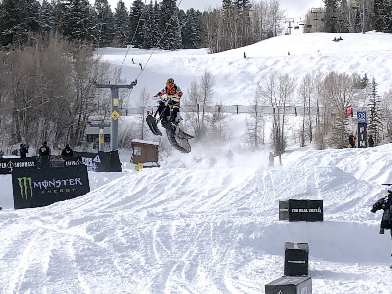 Someone riding a snowmobile riding down a snowy hill.