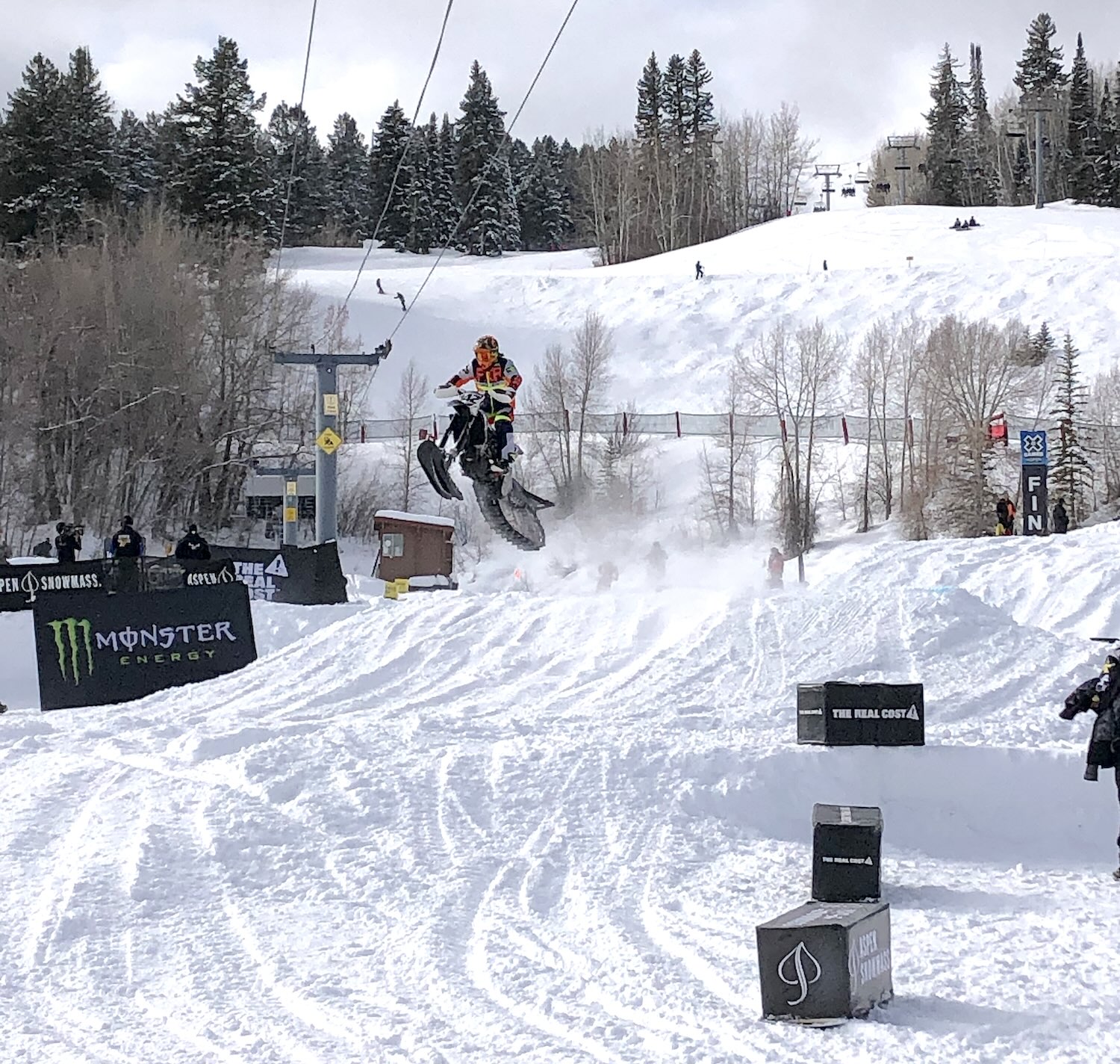 Someone riding a snowmobile riding down a snowy hill.