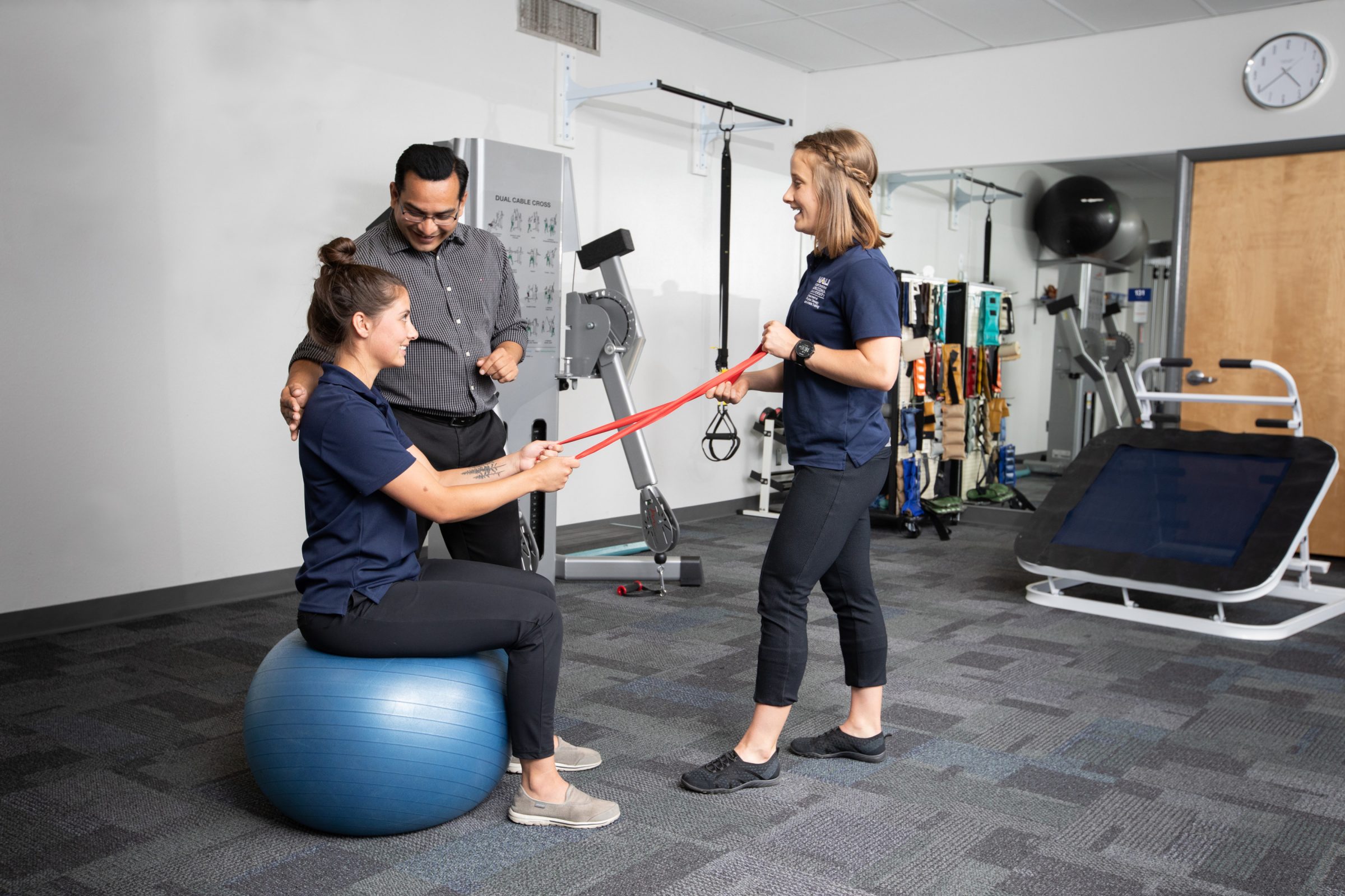 A physical therapist at N A U Flagstaff campus works with students on Bosu ball and exercise strap.