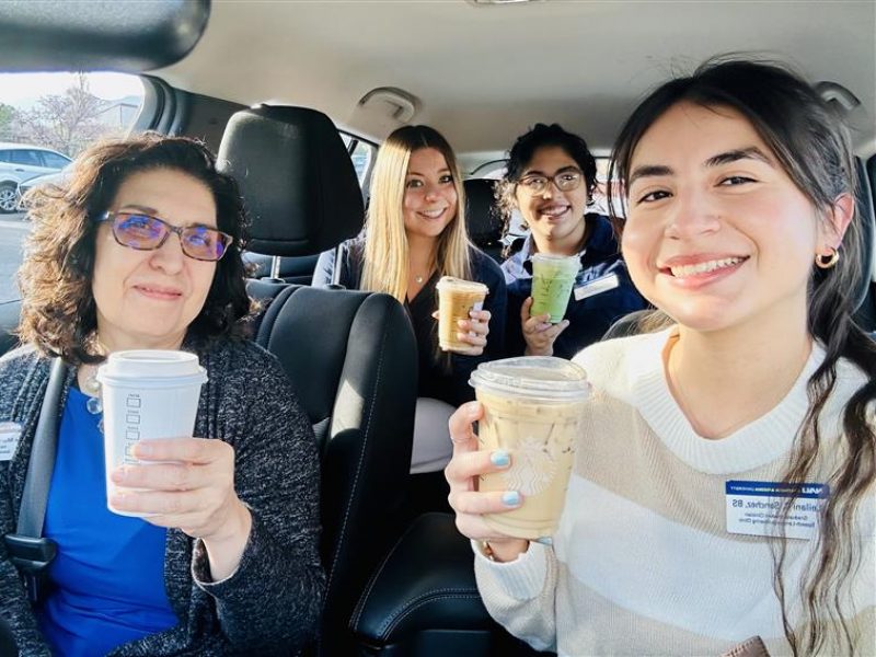 N A U Communication Sciences and Disorders students and professor Fe Murray holding coffee and smiling inside a vehicle.