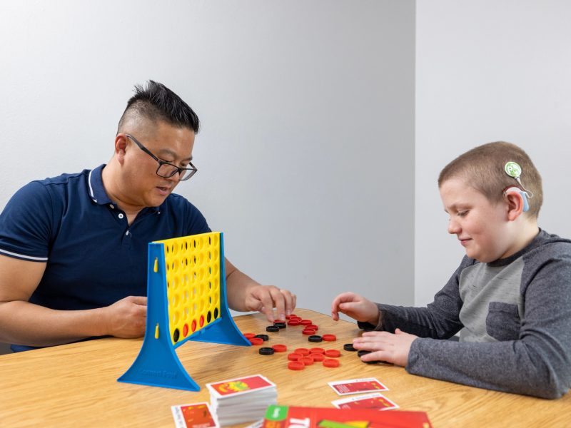 Two people playing connect 4 at table.