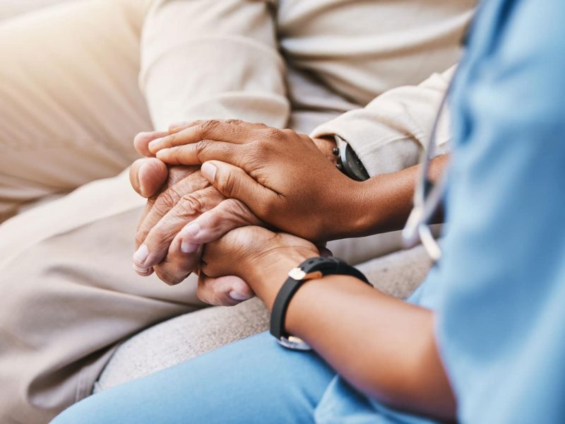 A women in scrubs holding a patient's hands.