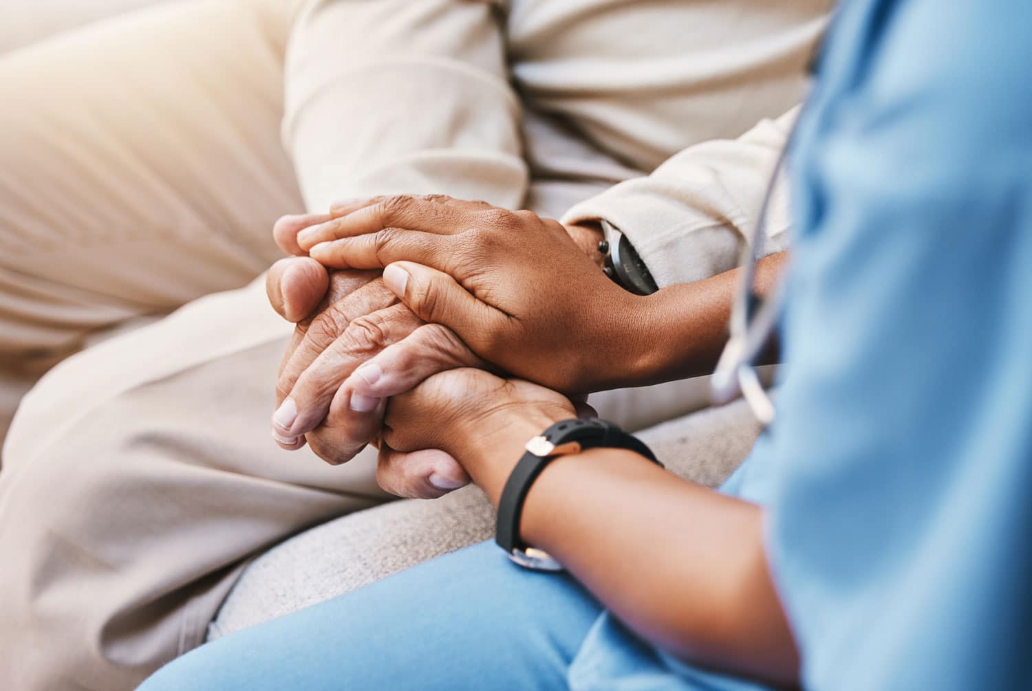 A women in scrubs holding a patient's hands.