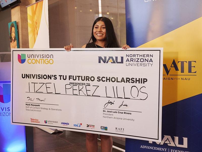 Mesa student wins full ride scholarship and holds check.
