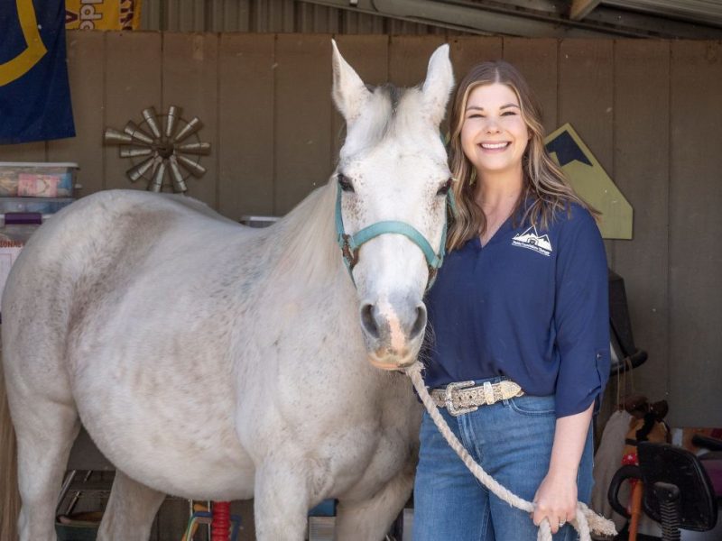 Lauren Hall standing with a white horse.