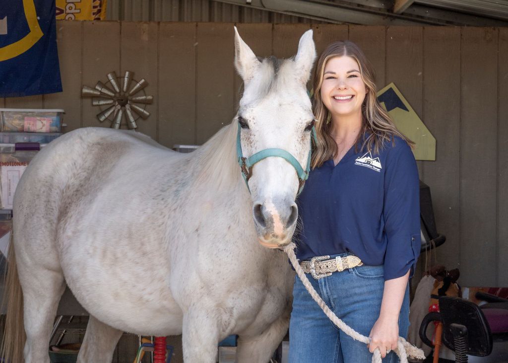 Lauren Hall standing with a white horse.