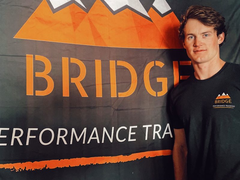 Briger Hershey posing in front of his gym's orange banner logo.