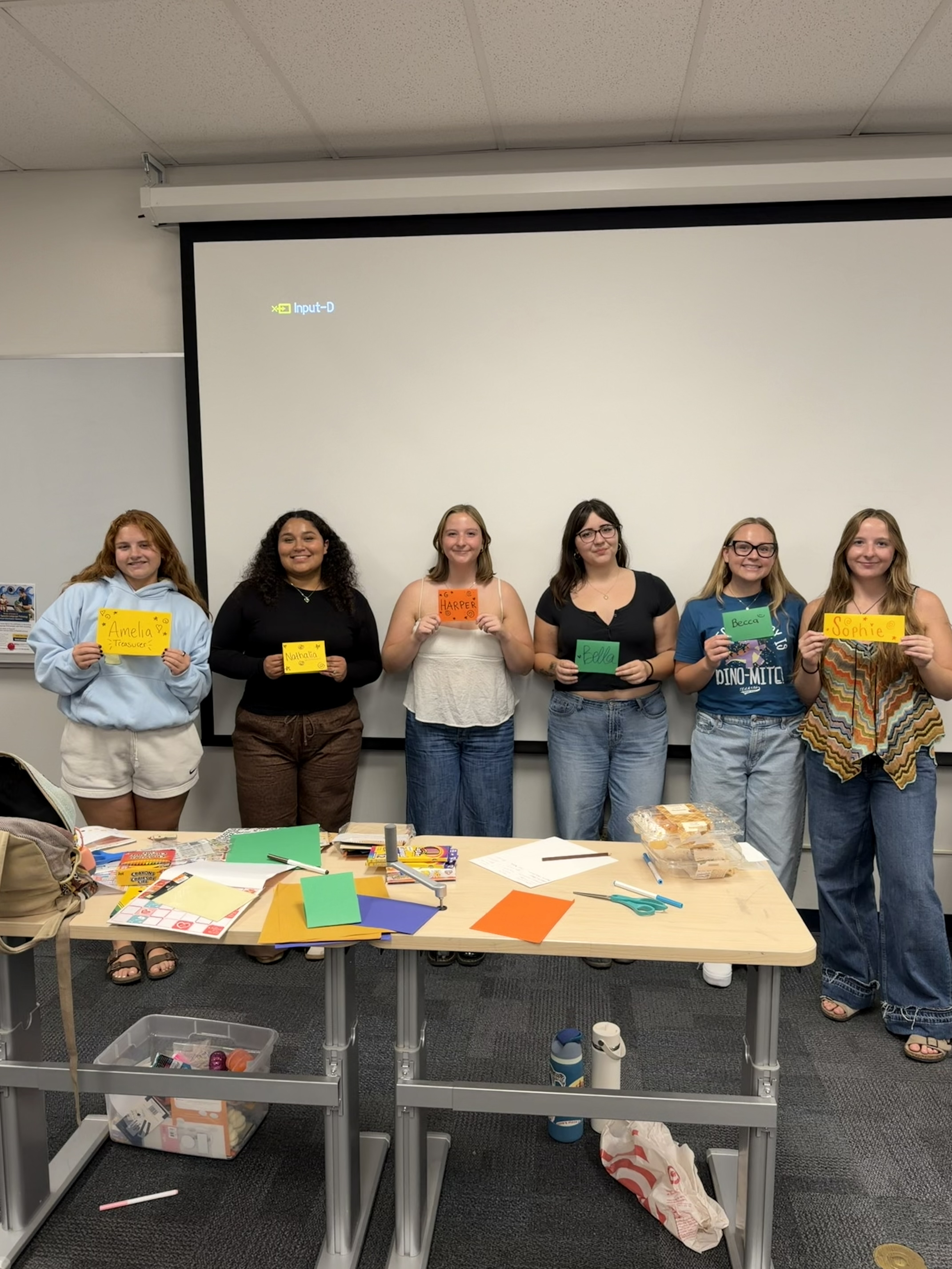 Nathalia Granados participating in SLP club related activities, posing in a line with five other girls at the front of a classroom. 