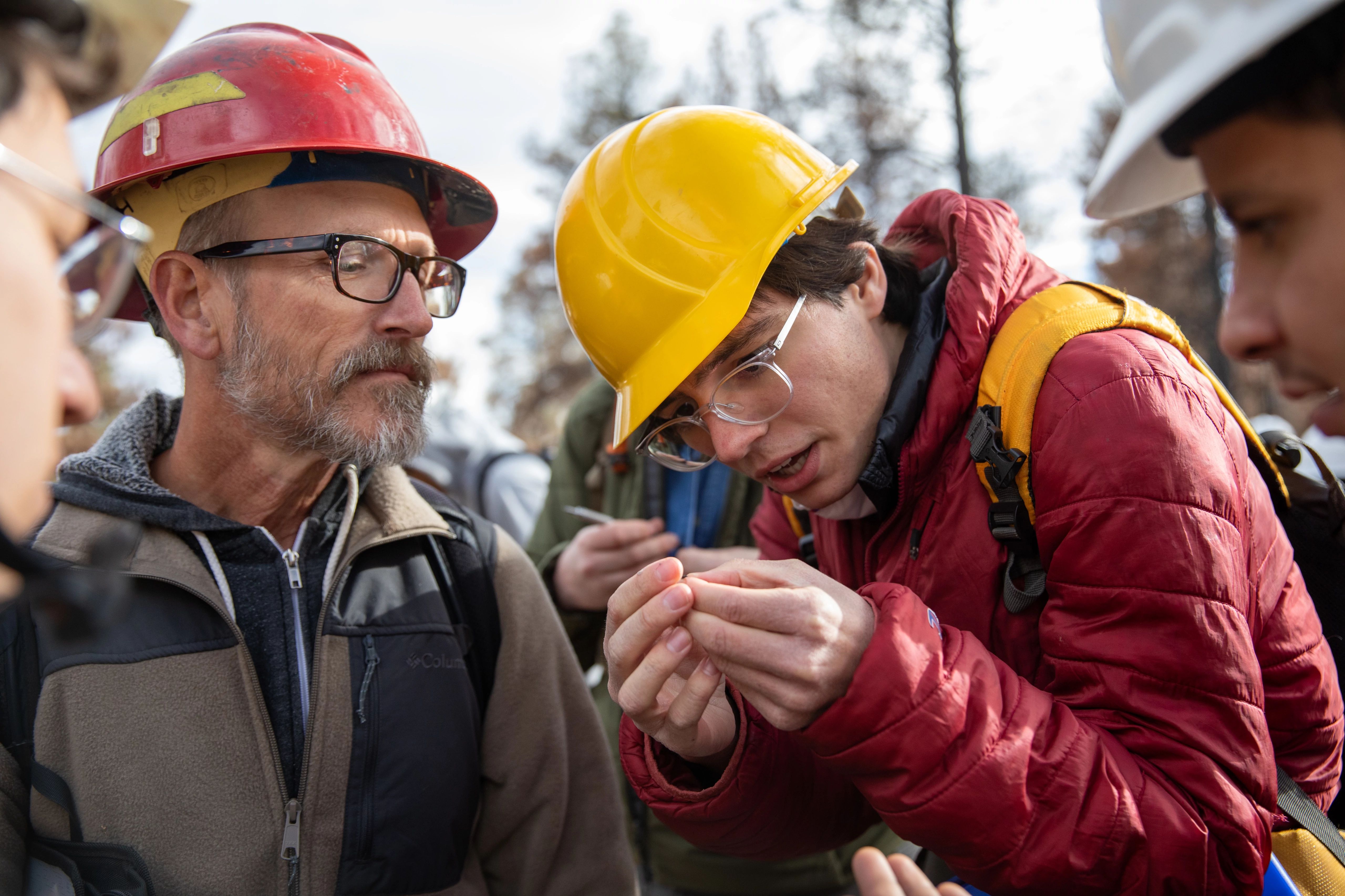 Faculty member and student wearing hard hats working outside