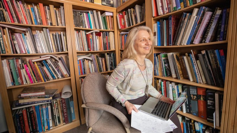 Suzsanna Gulacsi working on a computer and smiling into the distance.