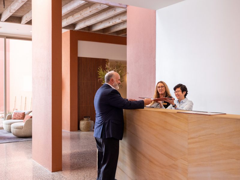 People standing at a front desk collaborating about something in a folder.