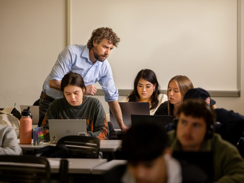A professor collaborating with students in a classroom.