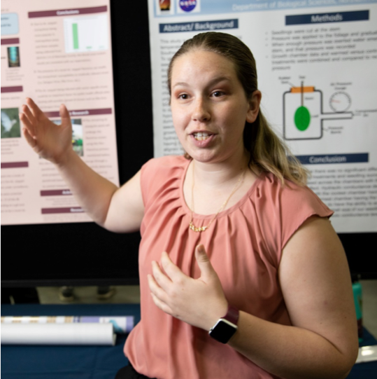 Undergraduate student researcher Daryn Erickson at the Undergraduate Symposium with her poster