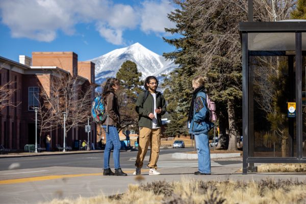 Three students talking on campus with the San Francisco Peaks in the background