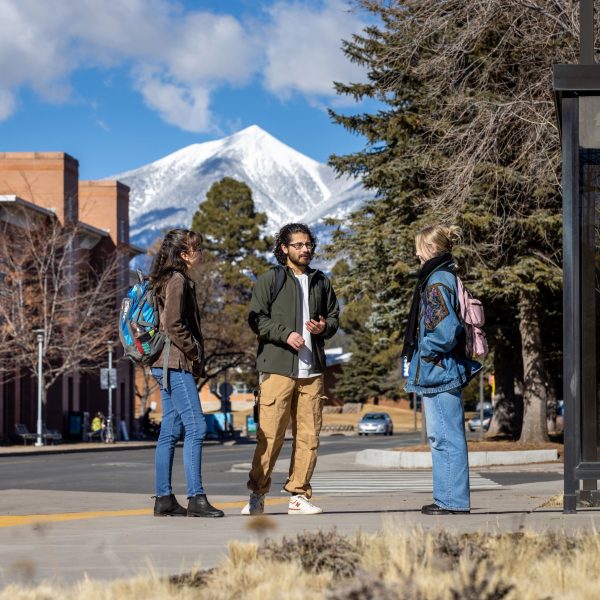 Three students talking on campus with the San Francisco Peaks in the background
