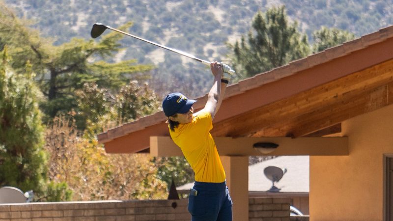 H R M golf tournament participant swings a club.