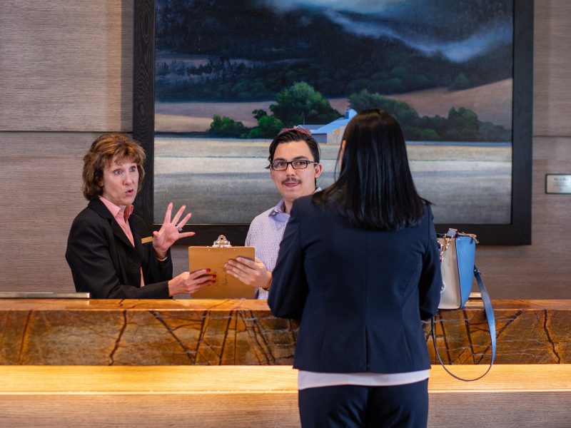 School of Hotel and Restaurant Management student and mentors working behind front desk at a partner hotel.