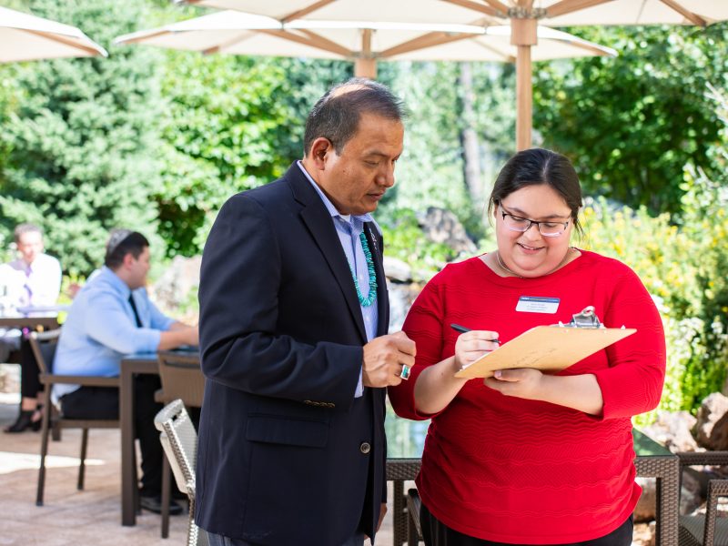 School of Hotel and Restaurant Management student and mentor standing together while referencing clipboard in front of them.