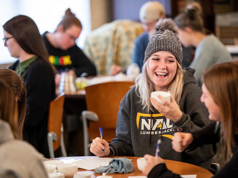 Hospitality student wearing NAU sweatshirt and hat practicing during a tea brewing and tasting demonstration.
