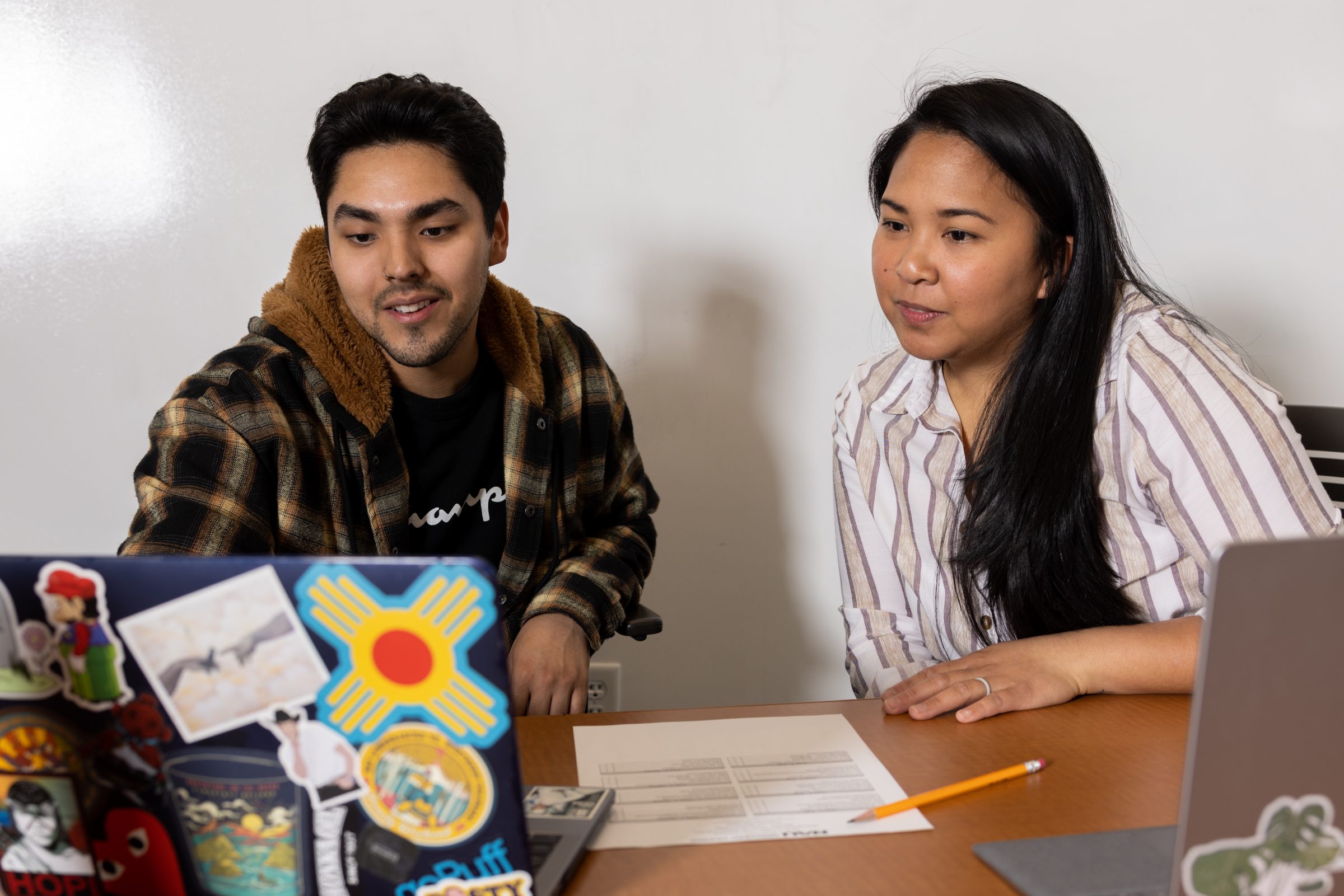 Two students looking at a laptop in the advising office.
