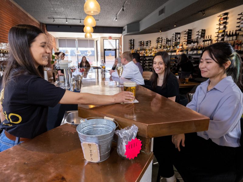 Student assisting customers at local bar.
