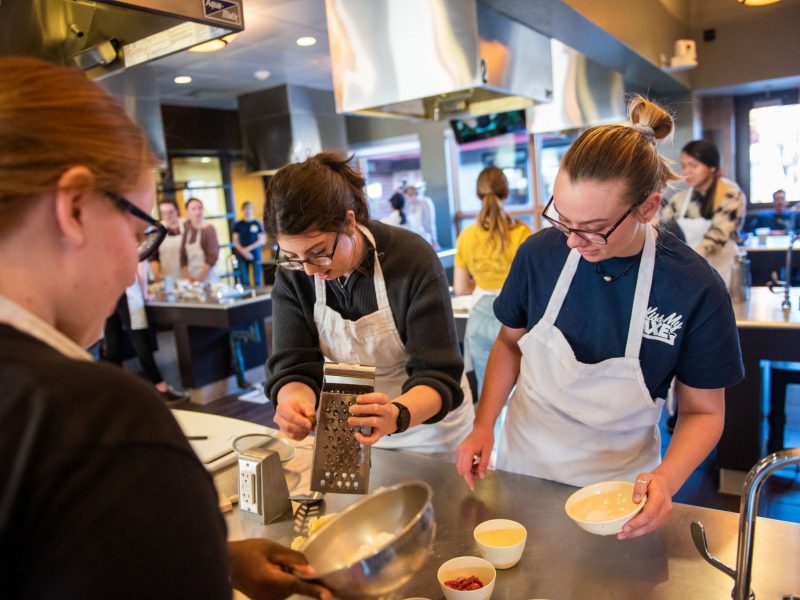 Three students preparing food in the culinary kitchen.