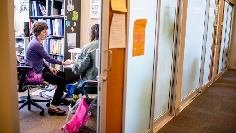 Professors meeting with students during office hours in the business building.