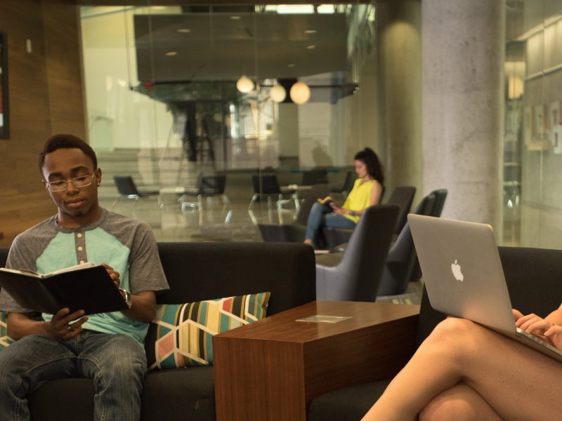 Students working on their laptops in a lounge.