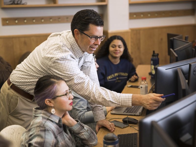 Professor assisting students on the computer.