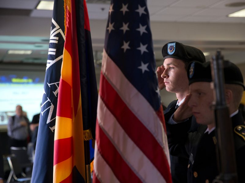 Military affiliated students presenting flags in traditional military attire at a veterans' convocation event.