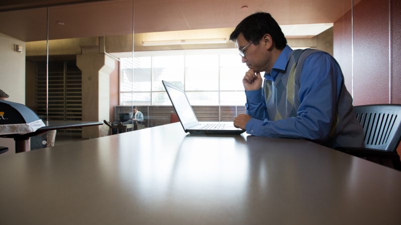 Professor working on their computer in a lounge.