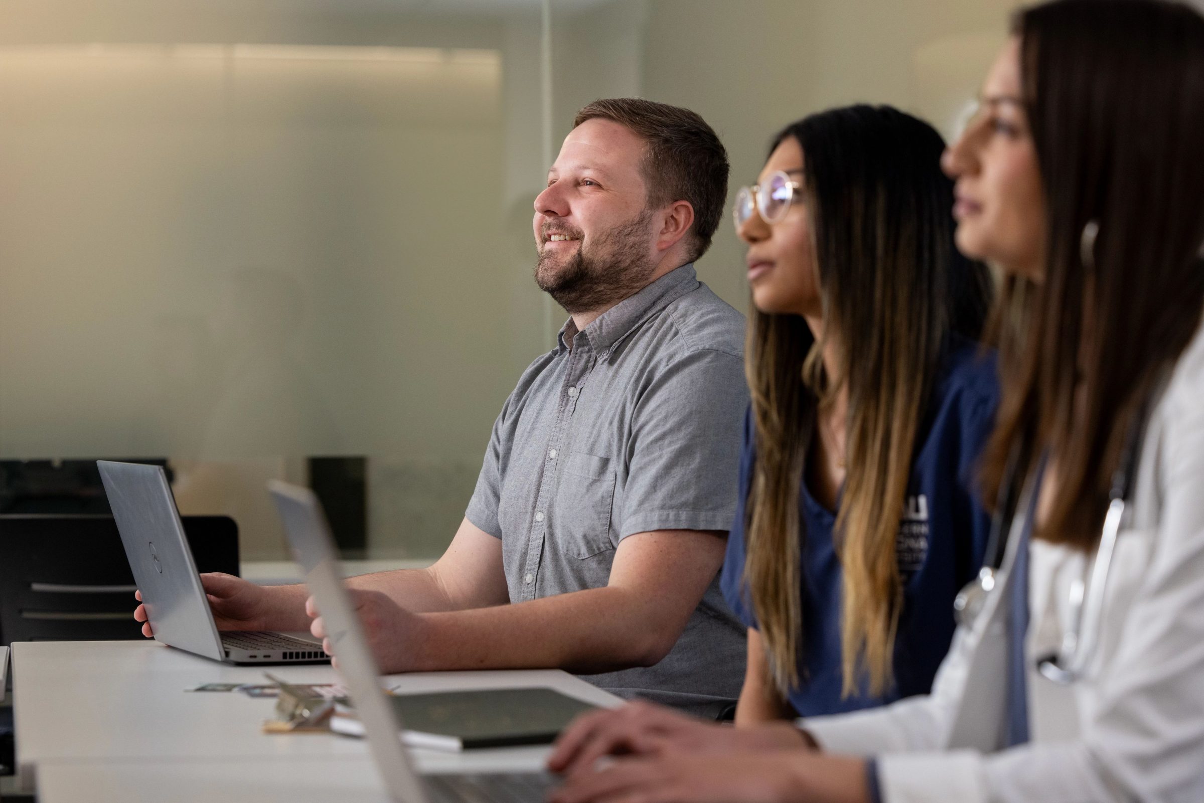 Three students in a classroom listening to a lecture.